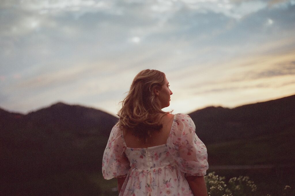 High school senior girl wearing a floral dress, posing for senior portraits at Guardsman Pass in Park City Utah by Austin Texas photographer.