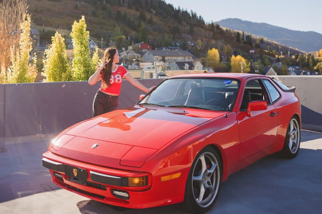 Group of stylish high school seniors posing with a vintage red Porsche in downtown Park City, Utah, for a senior rep team photoshoot.