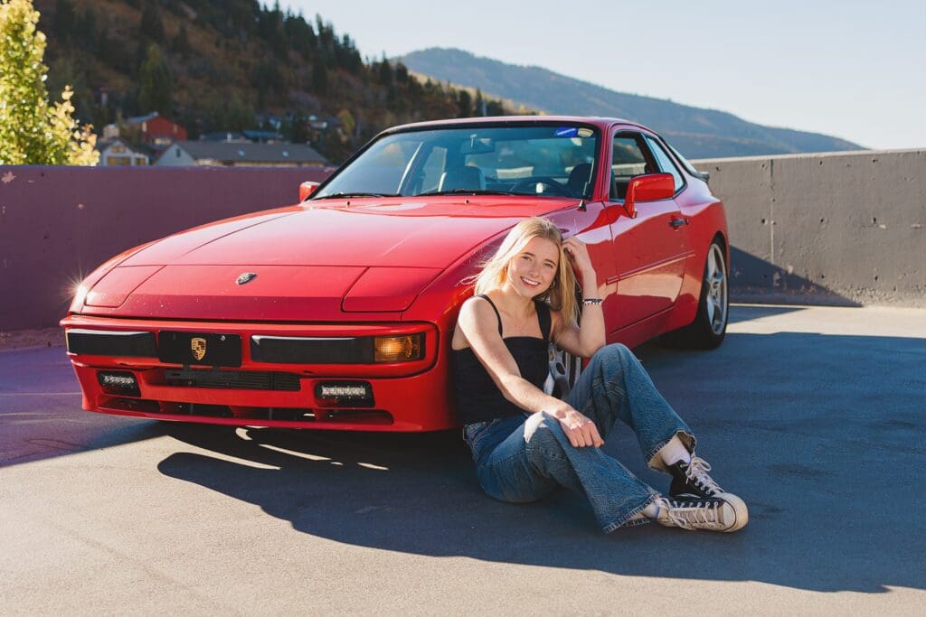 Group of stylish high school seniors posing with a vintage red Porsche in downtown Park City, Utah, for a senior rep team photoshoot.