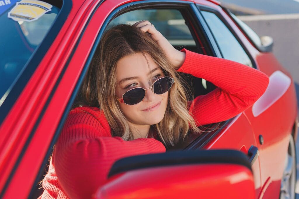 Group of stylish high school seniors posing with a vintage red Porsche in downtown Park City, Utah, for a senior rep team photoshoot.