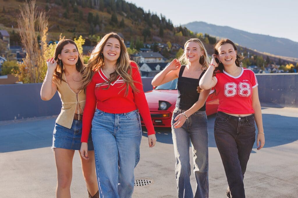 Group of stylish high school seniors posing with a vintage red Porsche in downtown Park City, Utah, for a senior rep team photoshoot.